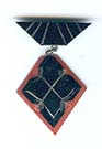 Pin of art deco era of geometric diamond and trapezoid shapes coloured black and orange.